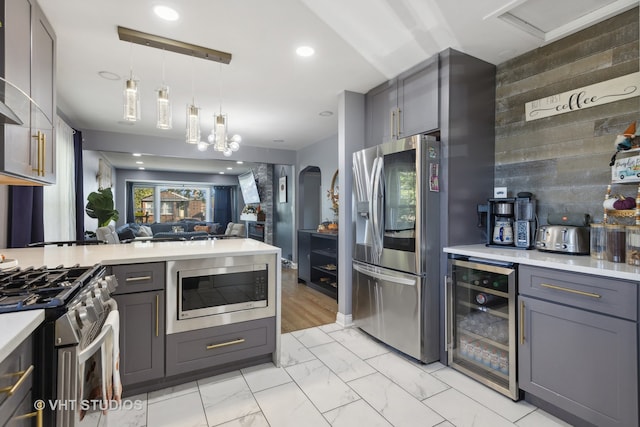 kitchen featuring gray cabinets, pendant lighting, wine cooler, decorative backsplash, and appliances with stainless steel finishes