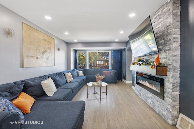 living room with light hardwood / wood-style flooring and a stone fireplace