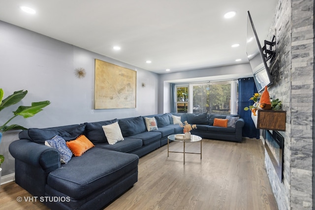 living room featuring wood-type flooring and a stone fireplace