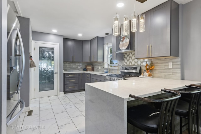 kitchen with kitchen peninsula, decorative light fixtures, gray cabinets, appliances with stainless steel finishes, and a kitchen breakfast bar