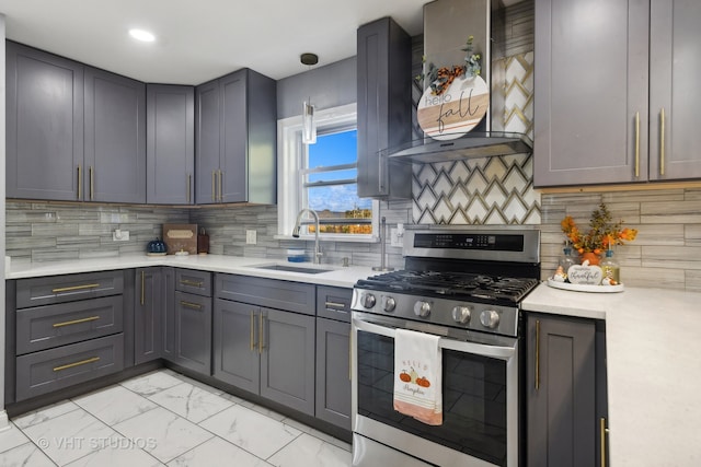 kitchen featuring tasteful backsplash, sink, stainless steel gas range, gray cabinetry, and wall chimney exhaust hood