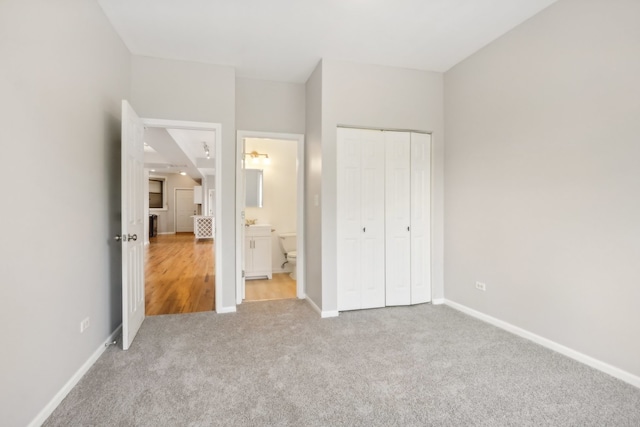 unfurnished bedroom with connected bathroom, light colored carpet, and a closet