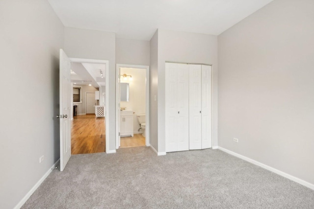 unfurnished bedroom with ensuite bathroom, a closet, and carpet