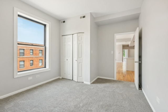 unfurnished bedroom featuring a closet and light colored carpet