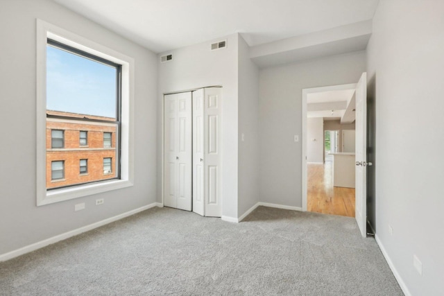 unfurnished bedroom featuring light colored carpet and a closet