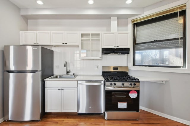 kitchen featuring sink, white cabinetry, tasteful backsplash, light wood-type flooring, and appliances with stainless steel finishes