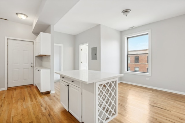 kitchen featuring a center island, white cabinetry, light hardwood / wood-style flooring, and electric panel