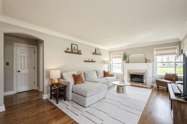living room featuring baseboards, ornamental molding, a fireplace with flush hearth, and wood finished floors