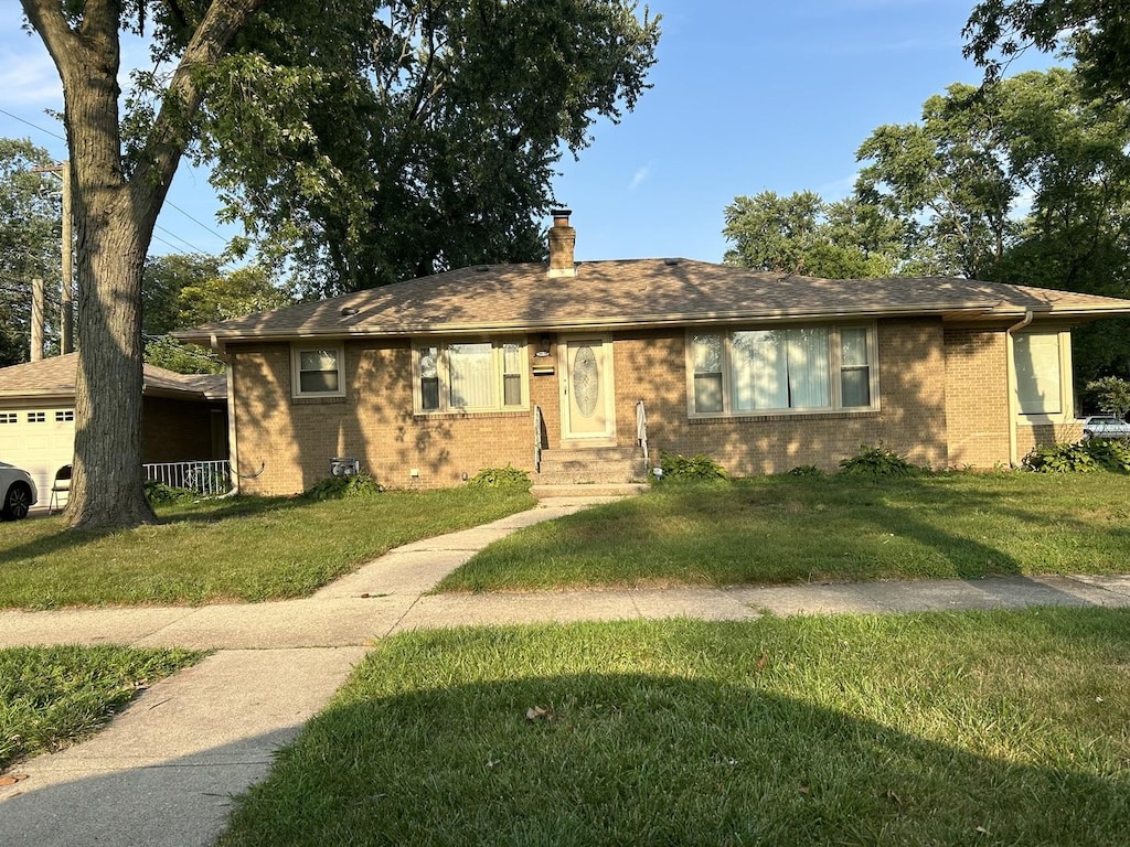 ranch-style house with a garage, brick siding, a chimney, and a front lawn