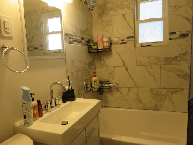 full bathroom featuring vanity, tiled shower / bath, and toilet