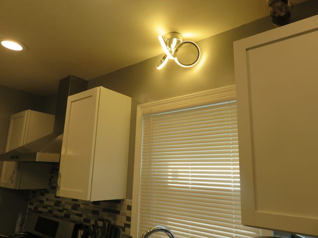 details with white cabinetry, decorative backsplash, and wall chimney exhaust hood