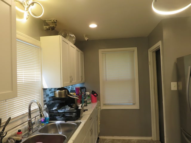 kitchen featuring sink, white cabinetry, and backsplash