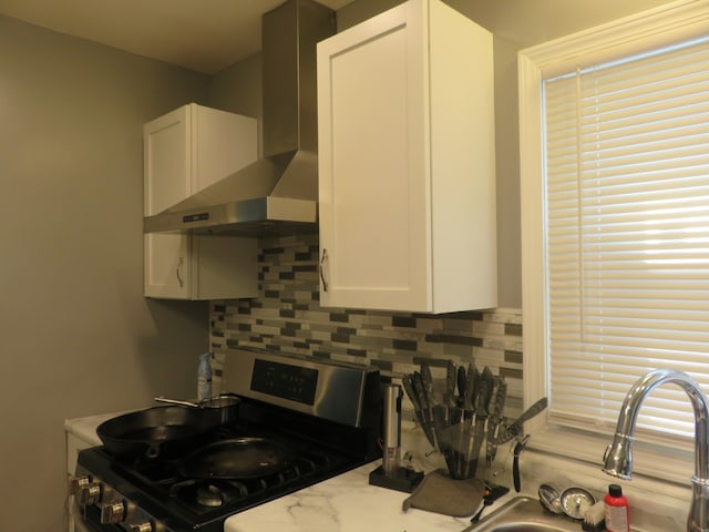 kitchen with white cabinetry, range, tasteful backsplash, and wall chimney exhaust hood