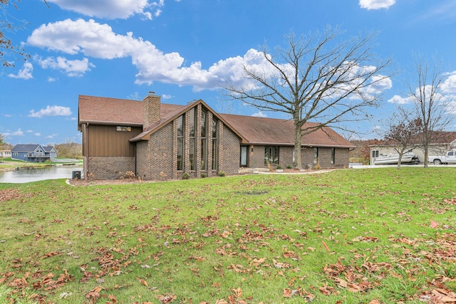 exterior space featuring driveway, brick siding, a lawn, and a chimney