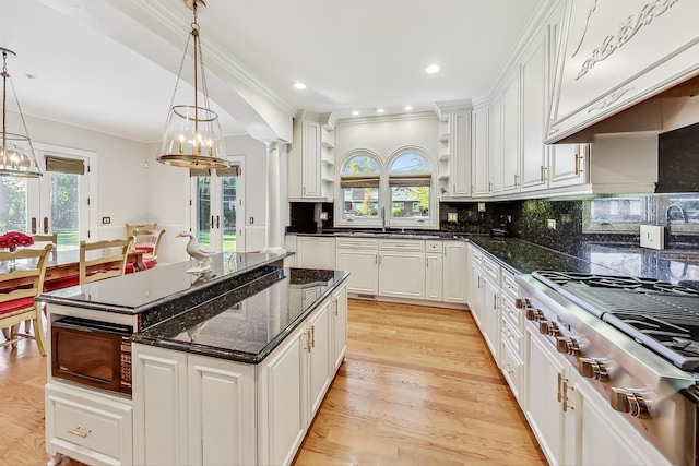 kitchen with decorative columns, white cabinets, black microwave, and light wood-type flooring