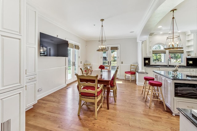 dining area with light hardwood / wood-style floors, crown molding, and sink