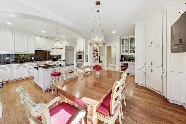 dining space with wine cooler, crown molding, and light wood-type flooring