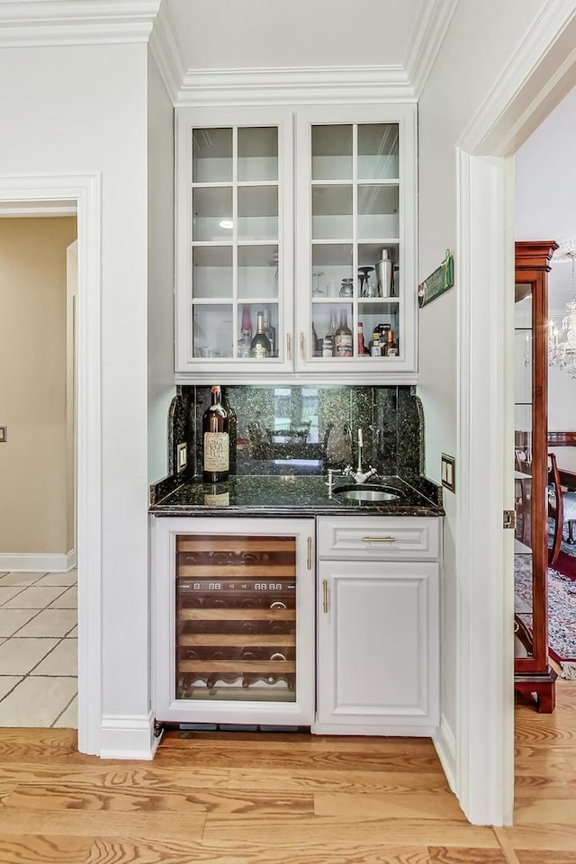 bar with light hardwood / wood-style floors, decorative backsplash, white cabinets, and beverage cooler