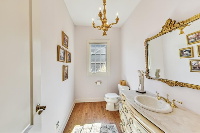 bathroom featuring vanity, toilet, hardwood / wood-style flooring, and a notable chandelier