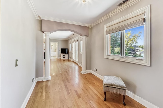 hall featuring ornate columns, ornamental molding, and light hardwood / wood-style flooring