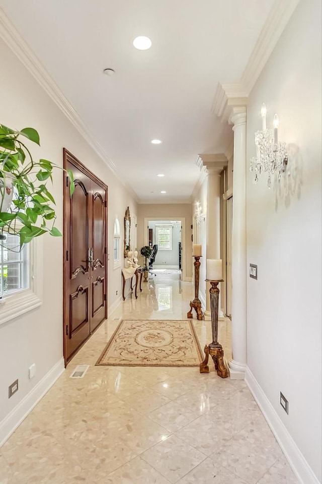 hallway with crown molding, ornate columns, and an inviting chandelier