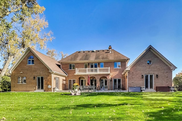 back of property with a patio area, a yard, and a balcony