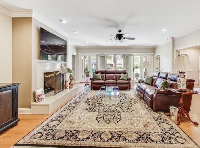 living room with ornamental molding, light wood-type flooring, and ceiling fan