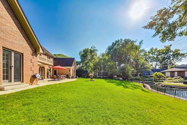 view of yard with a balcony, a trampoline, and a patio