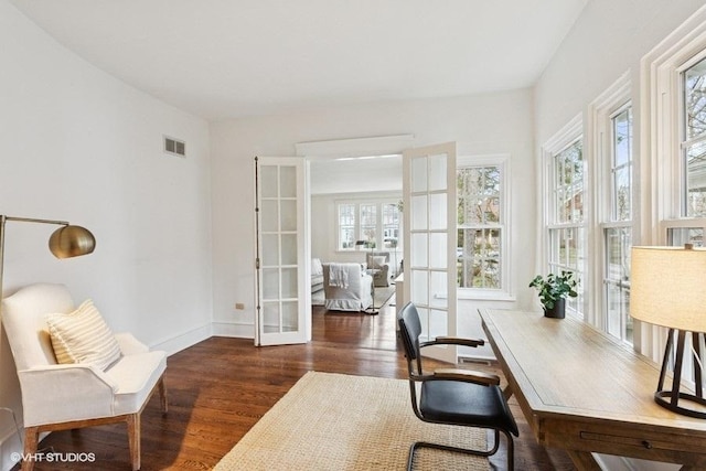 office featuring wood finished floors, baseboards, a healthy amount of sunlight, and visible vents