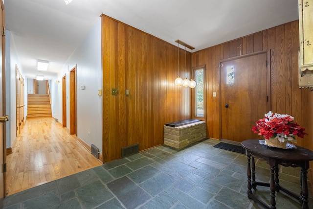 foyer entrance with wood walls and dark hardwood / wood-style floors