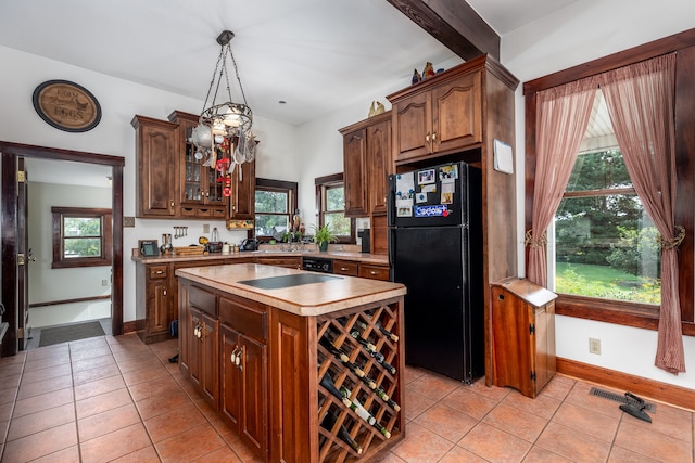 kitchen featuring a kitchen island, a healthy amount of sunlight, pendant lighting, and black appliances