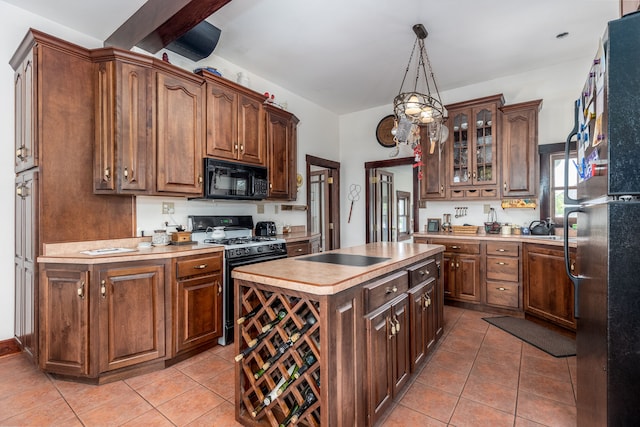 kitchen featuring hanging light fixtures, a kitchen island, light tile patterned floors, and black appliances