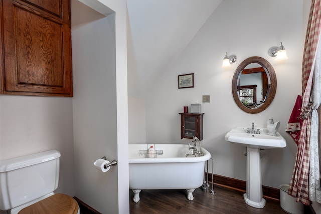 bathroom with vaulted ceiling, wood-type flooring, toilet, and a tub to relax in