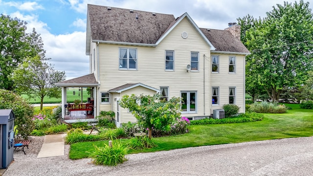 view of front of house with a front lawn, french doors, and central air condition unit