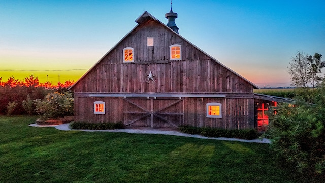 property exterior at dusk with an outdoor structure and a lawn