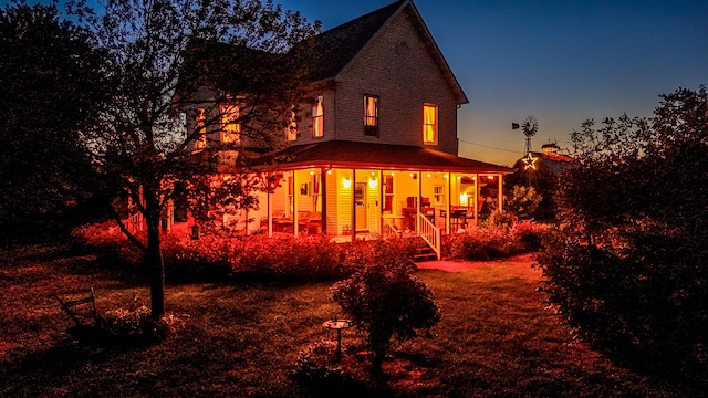 back house at dusk featuring covered porch