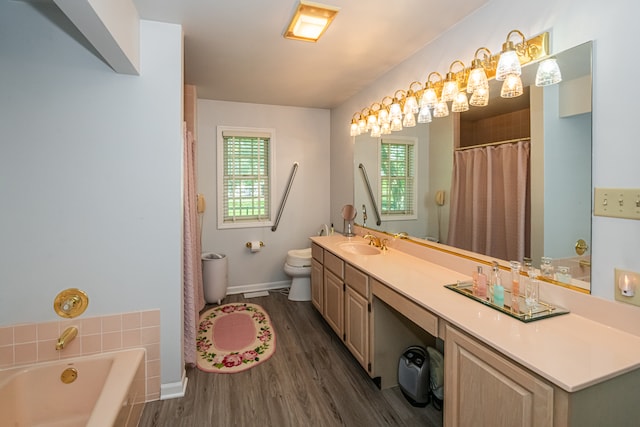 bathroom with hardwood / wood-style floors, a bath, toilet, and vanity