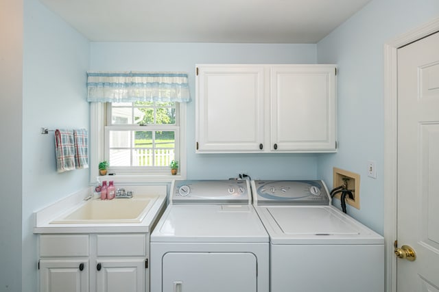 clothes washing area featuring sink, washing machine and dryer, and cabinets