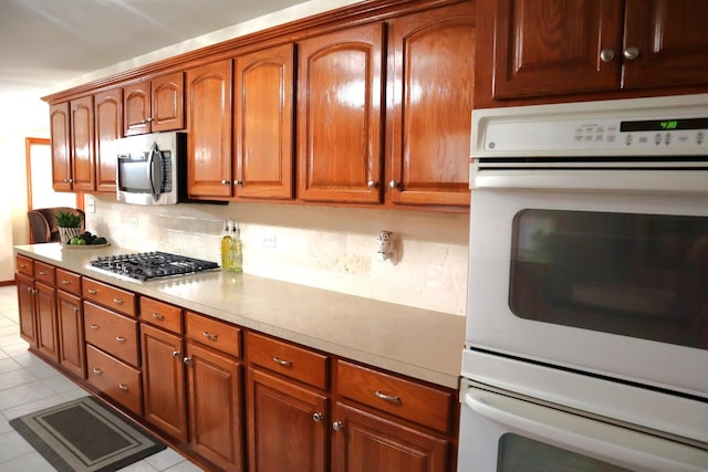 kitchen featuring stainless steel appliances, decorative backsplash, and light tile patterned floors