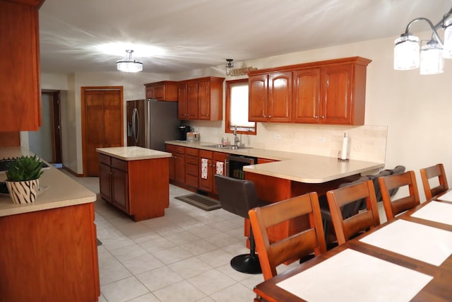 kitchen featuring a breakfast bar area, a center island, stainless steel fridge, sink, and kitchen peninsula