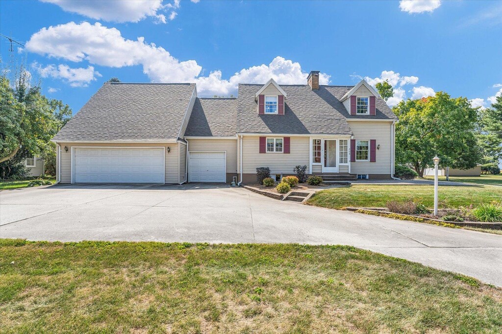 cape cod house with a front yard and a garage