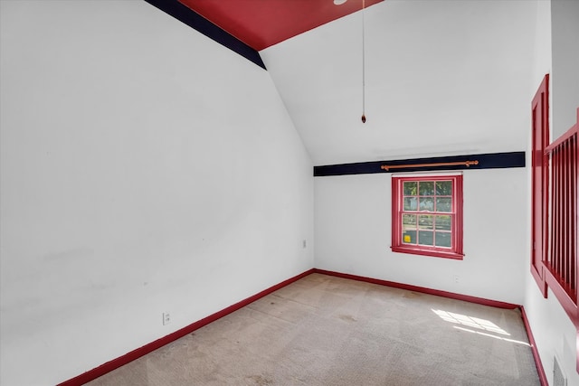 carpeted spare room with vaulted ceiling