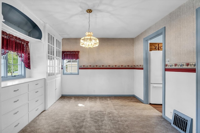 unfurnished dining area featuring carpet floors and an inviting chandelier