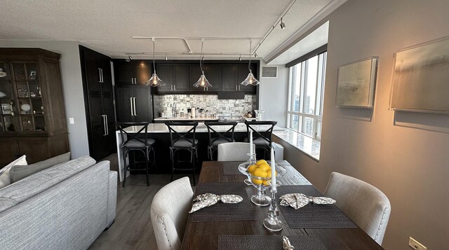 dining room featuring rail lighting, a textured ceiling, and hardwood / wood-style flooring