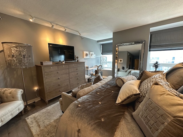 bedroom featuring rail lighting, a textured ceiling, and dark hardwood / wood-style flooring