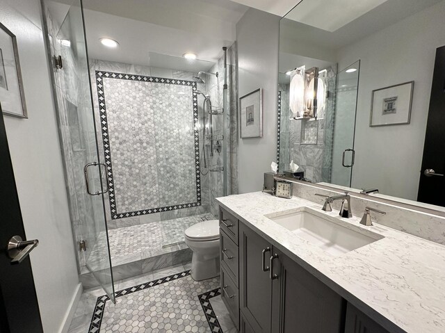 bathroom featuring toilet, tile patterned floors, vanity, and a shower with shower door