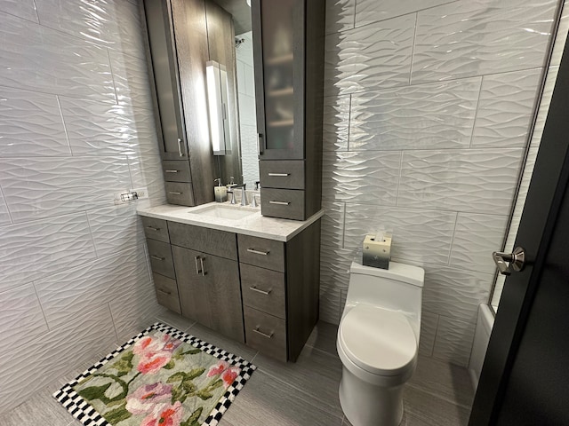 bathroom with tile patterned floors, tile walls, vanity, and toilet