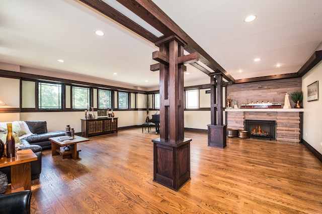 living room featuring beamed ceiling, decorative columns, and hardwood / wood-style flooring