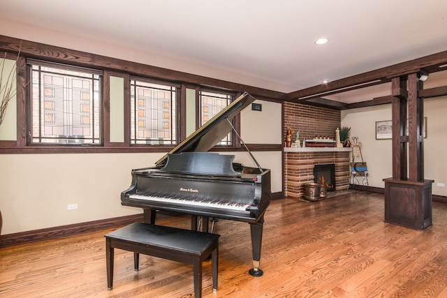 miscellaneous room with hardwood / wood-style flooring, a healthy amount of sunlight, a brick fireplace, and brick wall