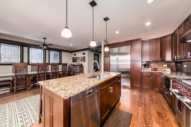 kitchen with premium appliances, light hardwood / wood-style flooring, an island with sink, and sink